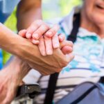 nurse consoling senior woman holding her hand